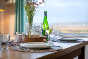a table with plates and glasses and a bottle of wine at Bay View Lodge, Brynowen in Borth