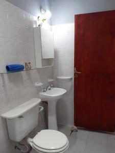 a bathroom with a toilet and a sink and a red door at Casa en Los Altos in Chilecito
