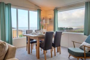 a dining room with a table and chairs and large windows at Bay View Lodge, Brynowen in Borth