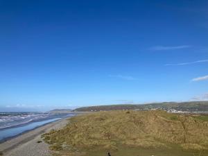 a person standing on a beach next to the ocean at Bay View Lodge, Brynowen in Borth