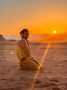 un hombre sentado en la playa al atardecer en Wadirum Zeid camp, en Wadi Rum