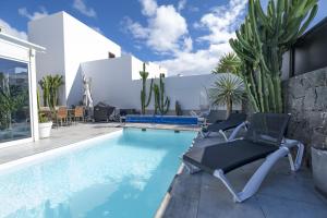 a swimming pool with two chairs next to a house at Casa Saidera in Playa Blanca