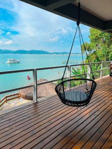 a porch with a swing overlooking the water at Casa pé na areia para até 14 pessoas em bombinhas in Bombinhas +19 photos