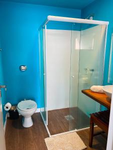 La salle de bains est pourvue de toilettes et d'une douche en verre. dans l'établissement Casa pé na areia para até 14 pessoas em bombinhas, à Bombinhas