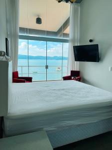 a bedroom with a large bed and a large window at Casa pé na areia para até 14 pessoas em bombinhas in Bombinhas