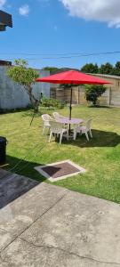 una mesa de picnic con una sombrilla roja en la hierba en @Canruss self catering accommodation, en Sunridge Park