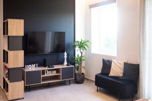 a living room with a flat screen tv and a chair at Live the Local Life , Old Town Kos in Kos