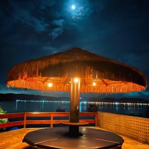 a straw umbrella sitting on top of a table at Casa pé na areia para até 14 pessoas em bombinhas in Bombinhas