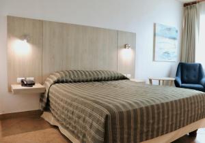 sypialnia z dużym łóżkiem i niebieskim krzesłem w obiekcie Palmar Del Sol Hotel w mieście Quevedo
