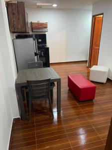 eine Küche mit einem Tisch und einer roten Ottomane in der Unterkunft Apt estudio calle97301 in Bogotá