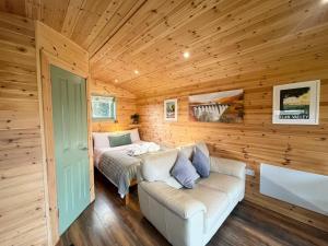 ein Schlafzimmer mit einem Bett und einem Sofa in einem Holzzimmer in der Unterkunft Hwyl in Abbey-Cwmhir