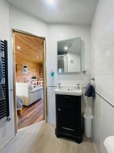 ein Badezimmer mit einem Waschbecken und einem Spiegel sowie ein Wohnzimmer in der Unterkunft Hwyl in Abbey-Cwmhir