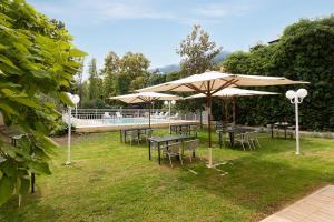 un groupe de tables et de parapluies dans l'herbe dans l'établissement Appart Hotel Corte HR, à Corte