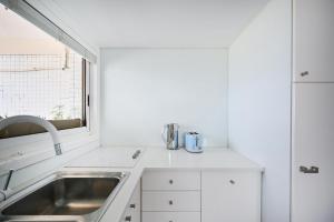 a white kitchen with a sink and a window at Stunning by HolyGuest in Tel Aviv
