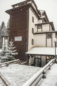 a building with a sign on it in the snow at Apartman Sakovic in Kopaonik