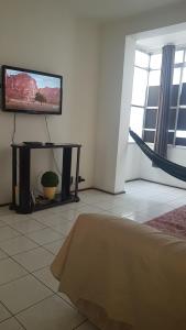 a living room with a flat screen tv on a wall at Pé na areia Gonzaguinha São Vicente in São Vicente