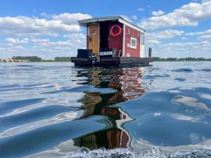 una casa en un muelle sobre un cuerpo de agua en Hausfloßvermietung auf der Peene am Kummerower See in Mecklenburg Vorpommern en Dargun