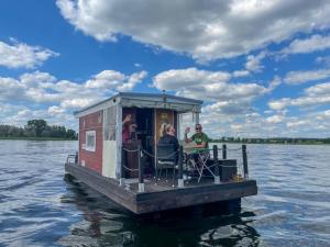 a group of people on a small boat on the water at Hausfloßvermietung auf der Peene am Kummerower See in Mecklenburg Vorpommern in Dargun