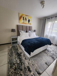 a bedroom with a large bed with a blue blanket at 2a - 64 No load shedding 2bed 2bath with garden in Centurion