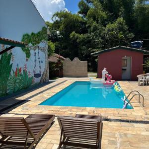 una pequeña piscina con 2 sillas y una casa en Chales da Lua Juquehy, en Juquei