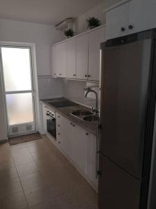 a kitchen with white cabinets and a stainless steel refrigerator at Rinconcito en Aguamarga in Agua Amarga