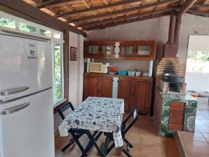a kitchen with a table and a white refrigerator at Pousada Beija flor in Extrema