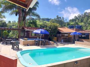 a swimming pool with umbrellas and a house at Pousada Beija flor in Extrema