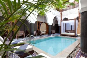 a pool in a hotel with a palm tree at Hotel & Spa Riad El Walaa in Marrakesh