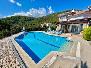 a swimming pool in front of a house at Family-Friendly 4 BR Villa with Pool and Garden - Fethiye in Fethiye