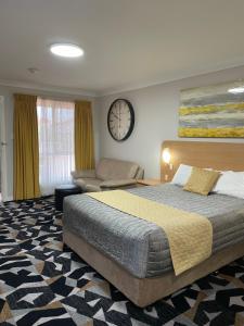 Cattlemans Country Motor Inn & Serviced Apartments في دوبو: غرفة نوم بسرير واريكة وساعة