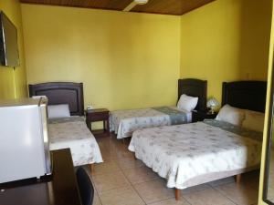 a room with two beds and a yellow wall at Hotel La Guaria in Liberia