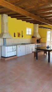 eine große Küche mit einem Tisch und gelben Wänden in der Unterkunft quinta vale da corga in Murça