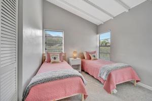 two beds in a room with two windows at Sunny Sanctuary in Marco Island