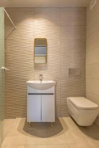 a bathroom with a white sink and a toilet at Elia & Anthos Deluxe Suites in Ixia