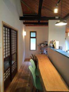 uma sala de jantar com uma mesa de madeira e cadeiras verdes em Satoyama Guest House Couture - Vacation STAY 43859v em Ayabe