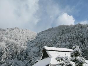 uma montanha coberta de neve com árvores e uma casa em Satoyama Guest House Couture - Vacation STAY 43859v em Ayabe