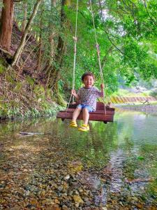 uma menina sentada num baloiço sobre um rio em Satoyama Guest House Couture - Vacation STAY 43859v em Ayabe