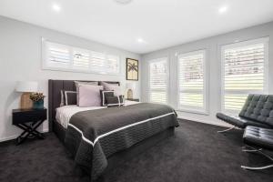 a bedroom with a bed and a chair and windows at Luxury at MacMasters Beach in Macmasters Beach