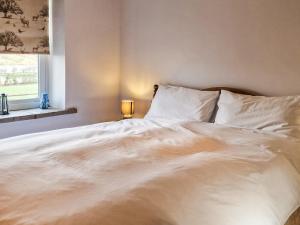 a bedroom with a large white bed with a window at The Barn in Blagdon