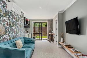 sala de estar con sofá azul y TV en Stagford Retreat Apartment - Taupo, en Taupo