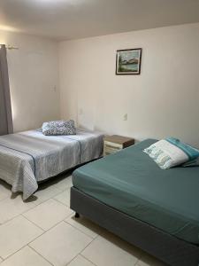 een slaapkamer met 2 bedden en een foto aan de muur bij Tia Denise Pousada in Penha