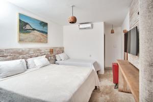1 dormitorio con 2 camas y TV de pantalla plana en Tamikuã Mar Pousada en Caraíva