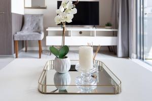 a living room with a glass table with vases and a tv at Menlyn Maine - The Trilogy Apartment 1111 in Pretoria