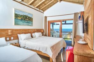 a hotel room with two beds and a balcony at Tamikuã Mar Pousada in Caraíva +29 photos
