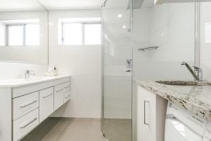 een witte badkamer met een douche en een wastafel bij Mingara 4 in Yamba