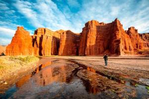 un hombre caminando por un desierto con grandes formaciones rocosas en Puesta del Sol en Salta