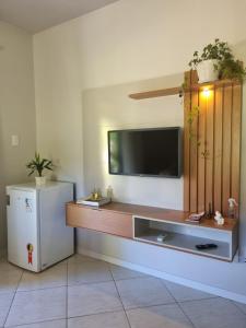 een woonkamer met een televisie en een koelkast bij Frieden Haus Pousada in Pomerode