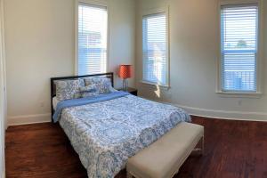 a bedroom with a bed with a blue comforter and windows at La Belle Veranda Villa- 3QueenBeds/2Baths Sleeps 6-8 in New Orleans