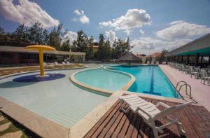 a large swimming pool with a bench and chairs at Sr.Flat Monte Castelo in Bezerros