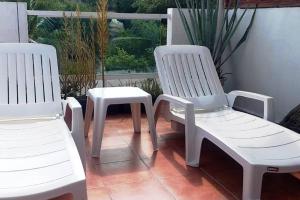 Duas cadeiras brancas e um banco numa varanda em Tu refugio en Tequesquitengo Casa once88 em Tlatenchu